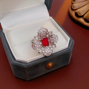 Detailed close-up of a flower-shaped silver ring with a red gemstone in a velvet box
