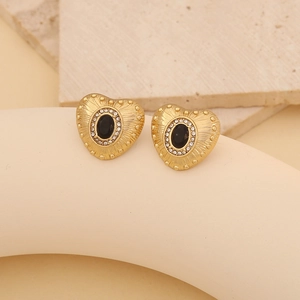 Detail of heart-shaped gold studs featuring black oval stones and white zircon accents