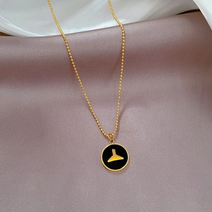 Close-up of golden mermaid tail pendant with black enamel on soft satin fabric
