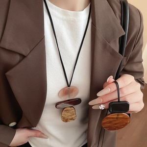 Detail of geometric resin pendant necklace with amber and red accents on long black cord