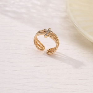 Macro detail of golden twisted band ring featuring a sparkling zircon cross design