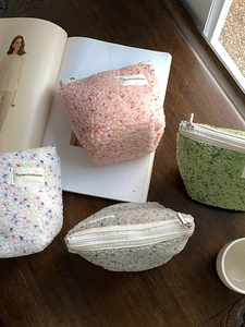 Dettaglio di pochette in pile colorato su un tavolo in legno con chiusura a zip