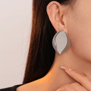 Detailed close-up of metallic striped shield earrings with silver needle on a model