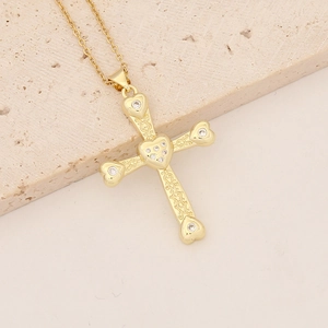 Detail of 18K gold plated cross pendant with heart engraving and cubic zirconia