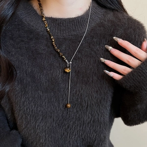 Detail view of tiger eye beaded necklace with silver chain on model in black sweater