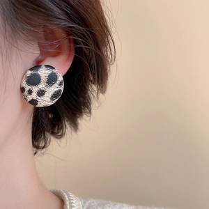 Gros plan de boucles d'oreilles rondes léopard avec une texture rétro élégante sur modèle