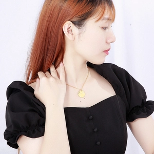 Detail of Aries gold coin pendant necklace with constellation engraving on model