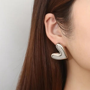 Polished silver heart-shaped hollow earrings made of stainless steel on female model