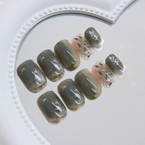 Short round press-on nails featuring green marble smudge design and leaf patterns