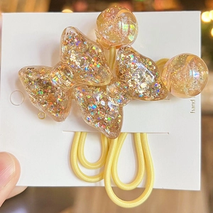 Macro view of colorful sequin-filled resin bow hair ties on white card packaging