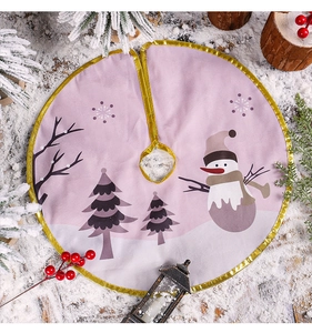 Detail of pink Christmas tree skirt with golden trim featuring snowman and snowflake prints
