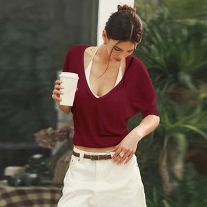 Detail of burgundy V-neck short sleeve top styled with a white halter neck camisole