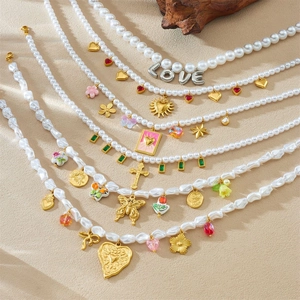 French style pearl necklace with gold heart charms and colorful beads on a beige surface