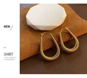 Macro detail of gold U-shaped earrings with textured horizontal ribbed finish