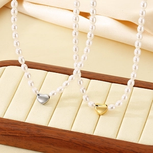 Elegant pearl necklace set with gold and silver heart pendants on display stand