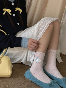 Close-up of pink mid-calf socks with black polka dots and cute cartoon embroidery