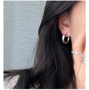 Close-up of minimalist S925 sterling silver C-shaped hoop earrings worn by a model