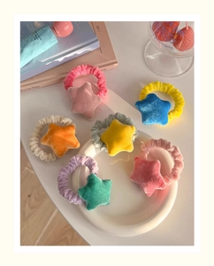 Colorful plush star hair scrunchies displayed with cute accessories on a white plate