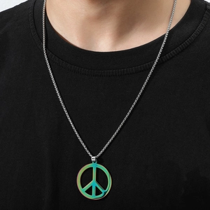 Macro detail of iridescent peace sign pendant with silver box chain on black t-shirt