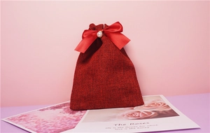 Dettaglio sacchetto regalo bordeaux in lino con fiocco di raso e decoro di perle