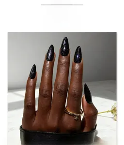 Détail d'ongles stiletto amande longs avec effet pailleté œil de chat noir et violet