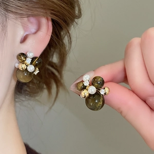 Detail of vintage gold stud earrings with olive green beads and white pearls on ear
