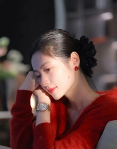 Close-up of luxury red flower resin earrings paired with a gold watch and knit sweater