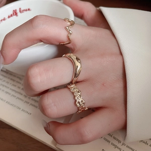 Close-up of three gold geometric stacking rings featuring wavy and smiley face designs