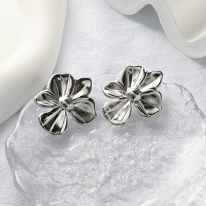 Macro view of realistic silver-finish five-petal flower stud earrings on textured tray