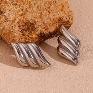 Macro shot of silver-tone triple-layered wave earrings on a textured stone surface