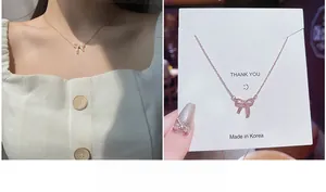 Dettaglio della collana con ciondolo a fiocco dorato e micro-pave di zirconi bianchi