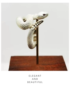 Macro detail of silver rattlesnake ring with golden tail accents and red stone eyes