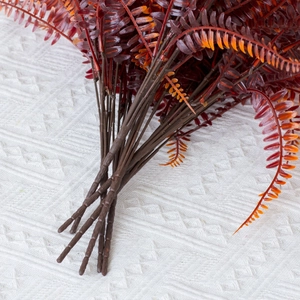 Close-up of artificial red Boston fern leaves showing realistic texture and vein details