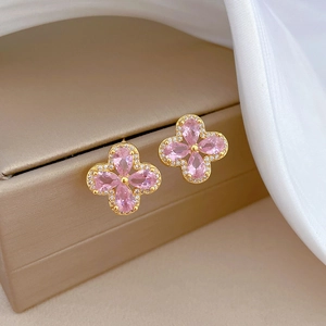 Pink clover earrings in gold finish with micro-inlaid diamonds on a luxury jewelry box