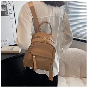 Detail of khaki faux leather backpack with litchi texture on a model in a modern room