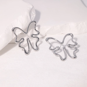 Close-up of silver hollow butterfly stud earrings on a minimalist stone background