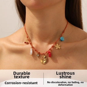 Detail of bohemian red braided necklace with gold tulip charms and colorful pendants