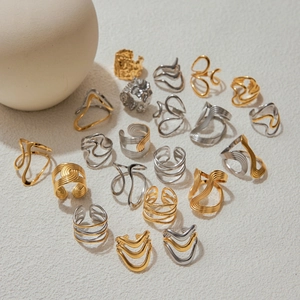 Detailed set of gold and silver wave texture rings and ear cuffs on textured background