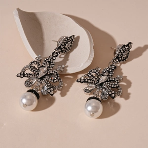 Detail of vintage silver bow earrings with sparkling rhinestones and drop pearls