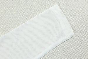 Détail du tissu en maille blanche montrant la texture respirante et la couture des poignets