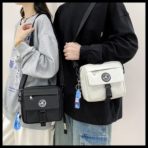 Couples wearing black and white tactical messenger bags with astronaut keychains
