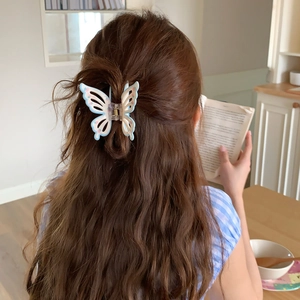 Detail of blue butterfly hair claw clip with floral pattern worn in a natural hairstyle