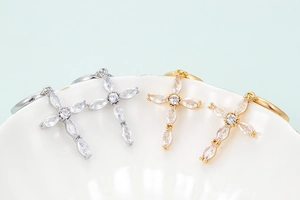 Cross drop earrings with marquise-cut zircons in gold and silver finish hanging on a bowl