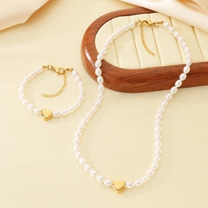 Detail of elegant faux pearl necklace and bracelet set with golden heart charms