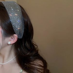 Detail of a wide headband with sparkling diamonds on female model with dark curly hair