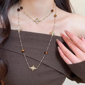 Close-up of a vintage golden cross necklace featuring tiger eye beads and crystals