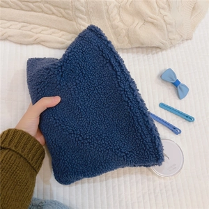Detail of soft navy blue fleece makeup bag held by hand against knit sweater