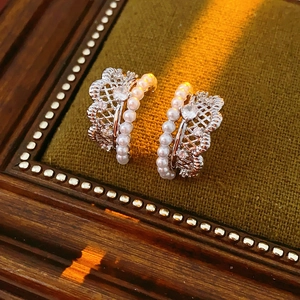 Detail of silver lace earrings with pearls and a central cubic zirconia stone