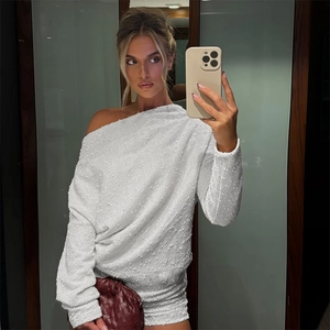 Λεπτομέρεια λευκού πλεκτού φορέματος με έξω ώμους και ανάγλυφη υφή με μακριά μανίκια