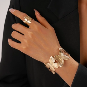 Detailed view of golden butterfly open cuff bracelets with textured metal finish on a model